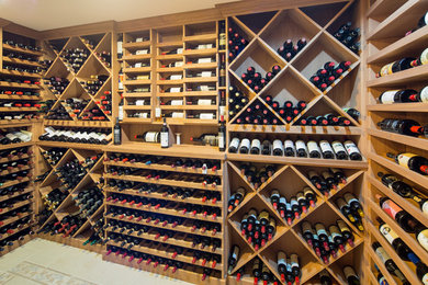 Example of a mid-sized farmhouse porcelain tile and beige floor wine cellar design in New York with display racks