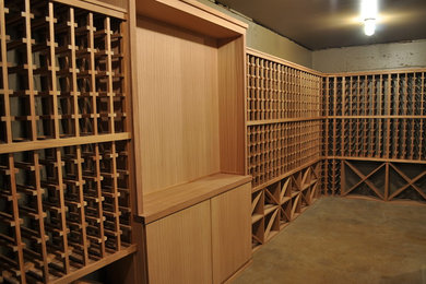 Wine cellar - mid-sized traditional concrete floor and brown floor wine cellar idea in Portland with display racks