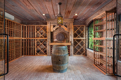 Exempel på en stor klassisk vinkällare, med tegelgolv och vinställ med diagonal vinförvaring