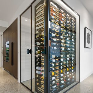 Immagine di una cantina contemporanea con pavimento in cemento, portabottiglie a vista e pavimento grigio