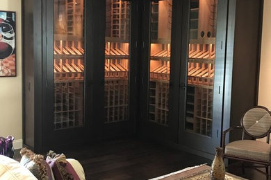 Bild på en mellanstor funkis vinkällare, med mörkt trägolv, vinhyllor och brunt golv