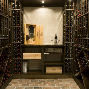 Imagen de bodega mediterránea con suelo de ladrillo, botelleros y suelo rojo