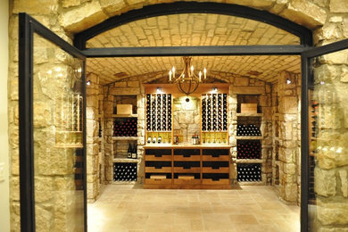 На фото: большой винный погреб в стиле ретро с полом из терракотовой плитки и витринами