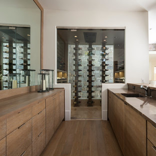Cette image montre une grand cave à vin design avec un sol en bois brun, un présentoir et un sol beige.