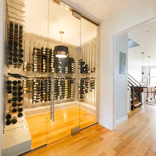 Réalisation d'une grand cave à vin design avec un sol en bois clair, un présentoir et un sol jaune.