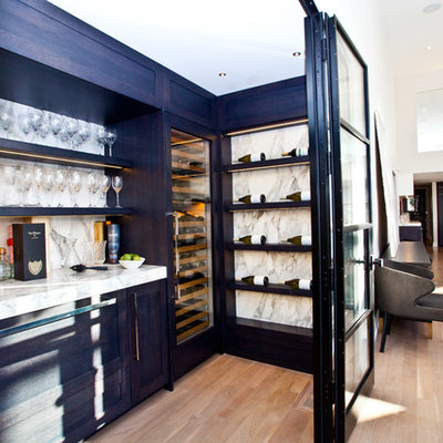 Example of a mid-sized transitional medium tone wood floor and beige floor wine cellar design in Toronto with display racks