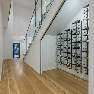Réalisation d'une cave à vin design avec un sol en bois clair, des casiers et un sol jaune.