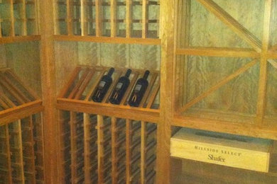 Mid-sized mountain style medium tone wood floor and brown floor wine cellar photo in Cedar Rapids with storage racks