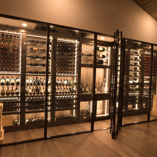 Immagine di una grande cantina design con pavimento in legno massello medio, portabottiglie a vista e pavimento marrone