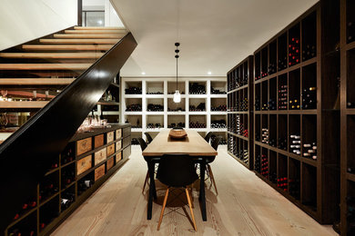 Medium sized modern wine cellar in Melbourne with display racks and light hardwood flooring.