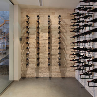 Immagine di una cantina minimal con pavimento in cemento, rastrelliere portabottiglie e pavimento grigio