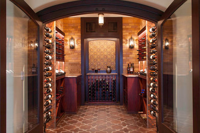 Wine cellar - large mediterranean terra-cotta tile and red floor wine cellar idea in San Diego with display racks