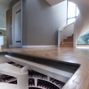 Imagen de bodega contemporánea, de tamaño medio, con suelo de madera oscura y botelleros