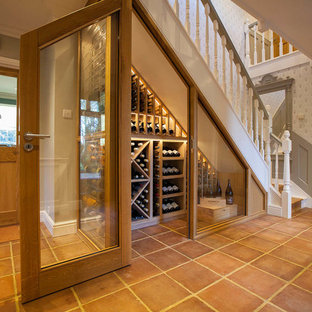 This is an example of a small traditional wine cellar in Essex with terracotta flooring, orange floors and cube storage.