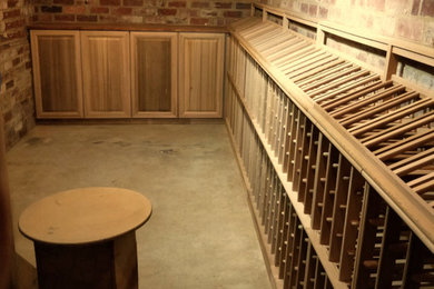 Exemple d'une cave à vin chic de taille moyenne avec sol en béton ciré, un présentoir et un sol gris.