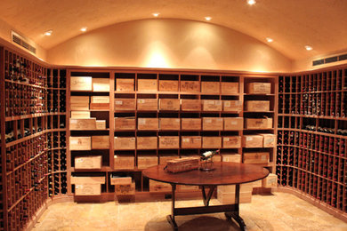 Wine cellar - large traditional travertine floor and beige floor wine cellar idea in Houston with storage racks