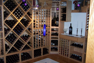 Bild på en stor funkis vinkällare, med mörkt trägolv och vinställ med diagonal vinförvaring