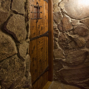Immagine di una cantina stile rurale di medie dimensioni con pavimento in pietra calcarea, rastrelliere portabottiglie e pavimento marrone