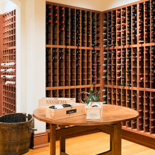 Foto de bodega clásica, grande, con suelo de madera clara, botelleros y suelo naranja