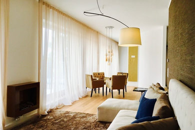 Repräsentatives, Offenes, Kleines Modernes Wohnzimmer mit brauner Wandfarbe, braunem Holzboden, Hängekamin, Kaminumrandung aus Metall, TV-Wand und braunem Boden in Berlin