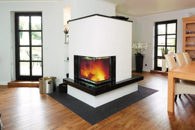 お手頃価格のコンテンポラリースタイルのおしゃれな応接間 (白い壁、無垢フローリング、コーナー設置型暖炉、石材の暖炉まわり) の写真
