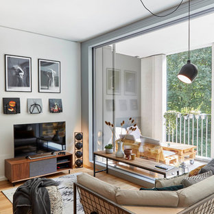 Modernes Wohnzimmer mit weißer Wandfarbe, braunem Holzboden, freistehendem TV und braunem Boden in München
