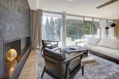 Modelo de sala de estar abierta contemporánea grande con suelo de madera clara, chimenea de doble cara, marco de chimenea de madera y suelo beige