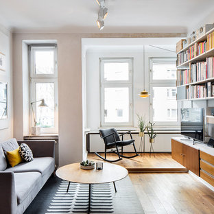 Nordische Bibliothek ohne Kamin mit weißer Wandfarbe, braunem Holzboden und freistehendem TV in Köln