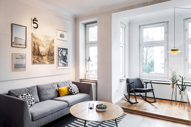 Diseño de sala de estar cerrada escandinava de tamaño medio sin chimenea con paredes blancas, suelo de madera en tonos medios y suelo marrón