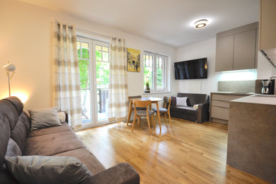 Kleines, Offenes Modernes Wohnzimmer ohne Kamin mit weißer Wandfarbe, braunem Holzboden, TV-Wand und braunem Boden in Sonstige