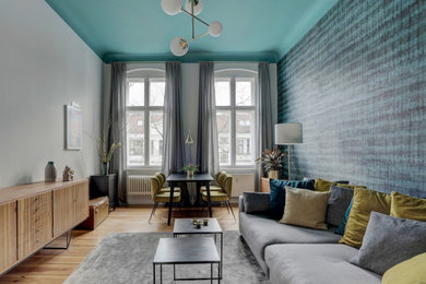 Großes, Fernseherloses, Abgetrenntes Retro Wohnzimmer mit blauer Wandfarbe, hellem Holzboden und braunem Boden in Berlin