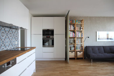 Mittelgroßes, Offenes, Fernseherloses Modernes Wohnzimmer ohne Kamin mit grauer Wandfarbe, braunem Holzboden und braunem Boden in Köln