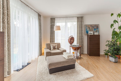 Mittelgroßes, Fernseherloses Modernes Wohnzimmer ohne Kamin mit weißer Wandfarbe, braunem Holzboden und braunem Boden in Sonstige