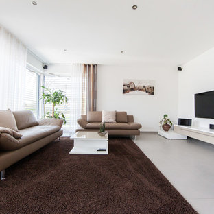 Mittelgroßes, Abgetrenntes Modernes Wohnzimmer mit weißer Wandfarbe, Tunnelkamin, Kaminumrandung aus Beton, Wand-TV und grauem Boden in Sonstige