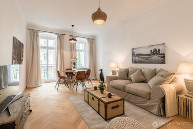 Mittelgroßes Wohnzimmer mit braunem Holzboden, braunem Boden und weißer Wandfarbe in Berlin