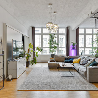 Offenes Stilmix Wohnzimmer mit weißer Wandfarbe, braunem Holzboden, freistehendem TV und braunem Boden in Frankfurt am Main