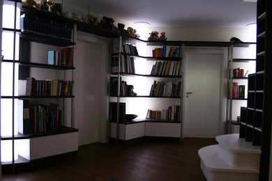Große Moderne Bibliothek im Loft-Stil mit weißer Wandfarbe und dunklem Holzboden in Hannover