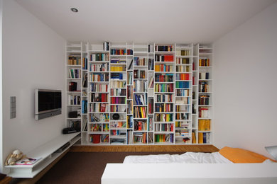 Mittelgroße, Offene Moderne Bibliothek mit weißer Wandfarbe, braunem Holzboden, TV-Wand und braunem Boden in Frankfurt am Main
