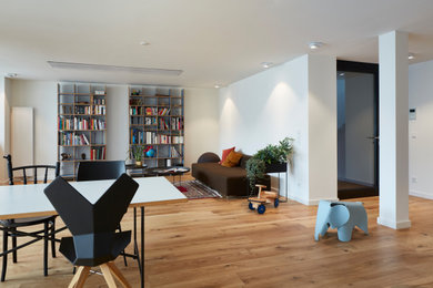 Modernes Wohnzimmer mit weißer Wandfarbe, hellem Holzboden und braunem Boden in Köln