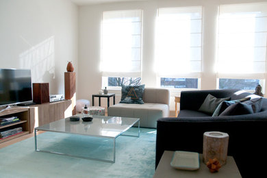 Imagen de salón abierto contemporáneo de tamaño medio con paredes blancas, suelo de madera clara, televisor independiente y suelo beige