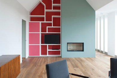 Idées déco pour un grand salon contemporain ouvert avec un mur bleu, un sol en bois brun, une cheminée standard, un manteau de cheminée en plâtre, un téléviseur encastré et un plafond cathédrale.