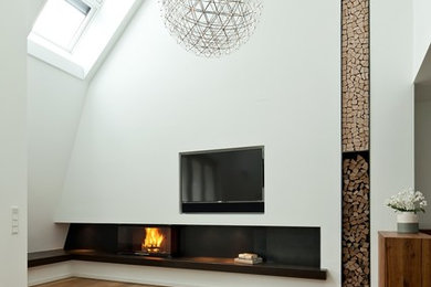 Großes Modernes Wohnzimmer im Loft-Stil mit weißer Wandfarbe, braunem Holzboden, Kaminofen, verputzter Kaminumrandung, TV-Wand und braunem Boden in München