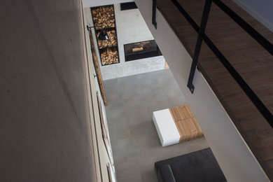 Geräumiges, Offenes Modernes Wohnzimmer mit grauer Wandfarbe, Eckkamin und Kaminumrandung aus Beton in Leipzig