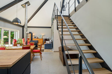 Großes, Repräsentatives, Offenes Modernes Wohnzimmer mit grauer Wandfarbe, braunem Holzboden, Kaminofen, Kaminumrandung aus Metall und braunem Boden in Berlin