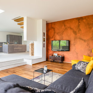 Mittelgroßes, Offenes Modernes Wohnzimmer mit weißer Wandfarbe, braunem Holzboden, Wand-TV und braunem Boden in Sonstige