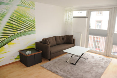 Kleines, Offenes Modernes Wohnzimmer ohne Kamin mit weißer Wandfarbe, hellem Holzboden, freistehendem TV und braunem Boden in Sonstige