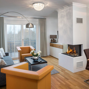 Kleines, Fernseherloses, Abgetrenntes Modernes Wohnzimmer mit weißer Wandfarbe, braunem Holzboden, Tunnelkamin, verputzter Kaminumrandung und braunem Boden in Sonstige