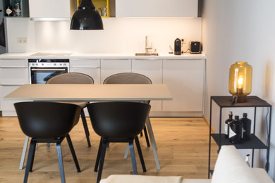 Mittelgroßes, Offenes Skandinavisches Wohnzimmer mit grauer Wandfarbe, hellem Holzboden und TV-Wand in Sonstige