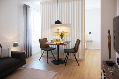 Mittelgroßes, Offenes Skandinavisches Wohnzimmer mit beiger Wandfarbe, Vinylboden, TV-Wand und braunem Boden in Sonstige