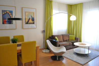 Abgetrenntes, Kleines Mid-Century Wohnzimmer ohne Kamin mit brauner Wandfarbe, Laminat, TV-Wand und braunem Boden in Berlin